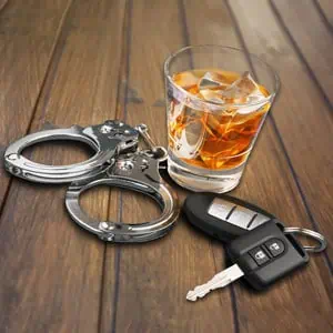  A wooden table displays car keys next to a bottle of alcohol, highlighting the DUI Jail Time before March Searches - The Inniss Firm, PLLC